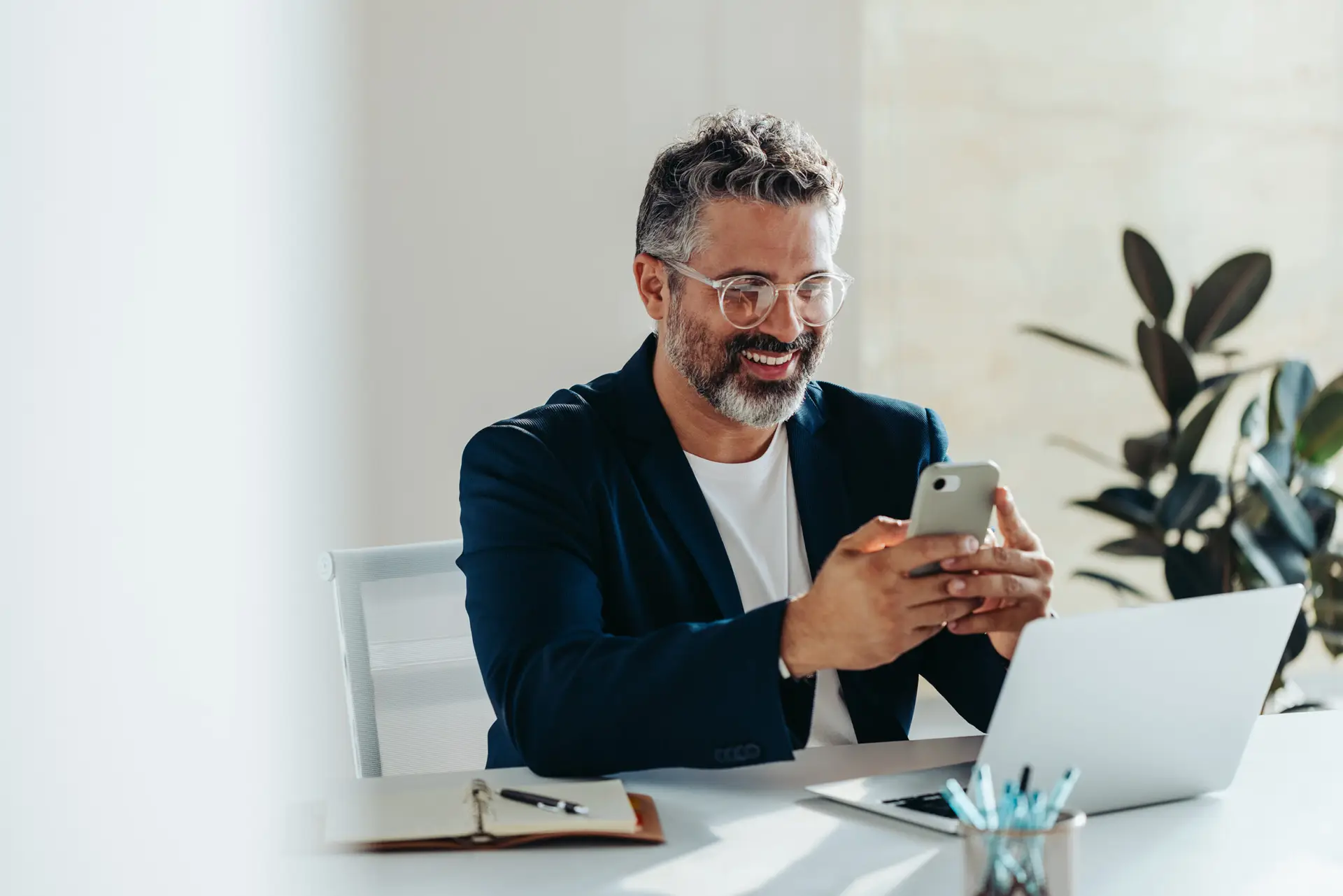 man looking at his phone at a desk