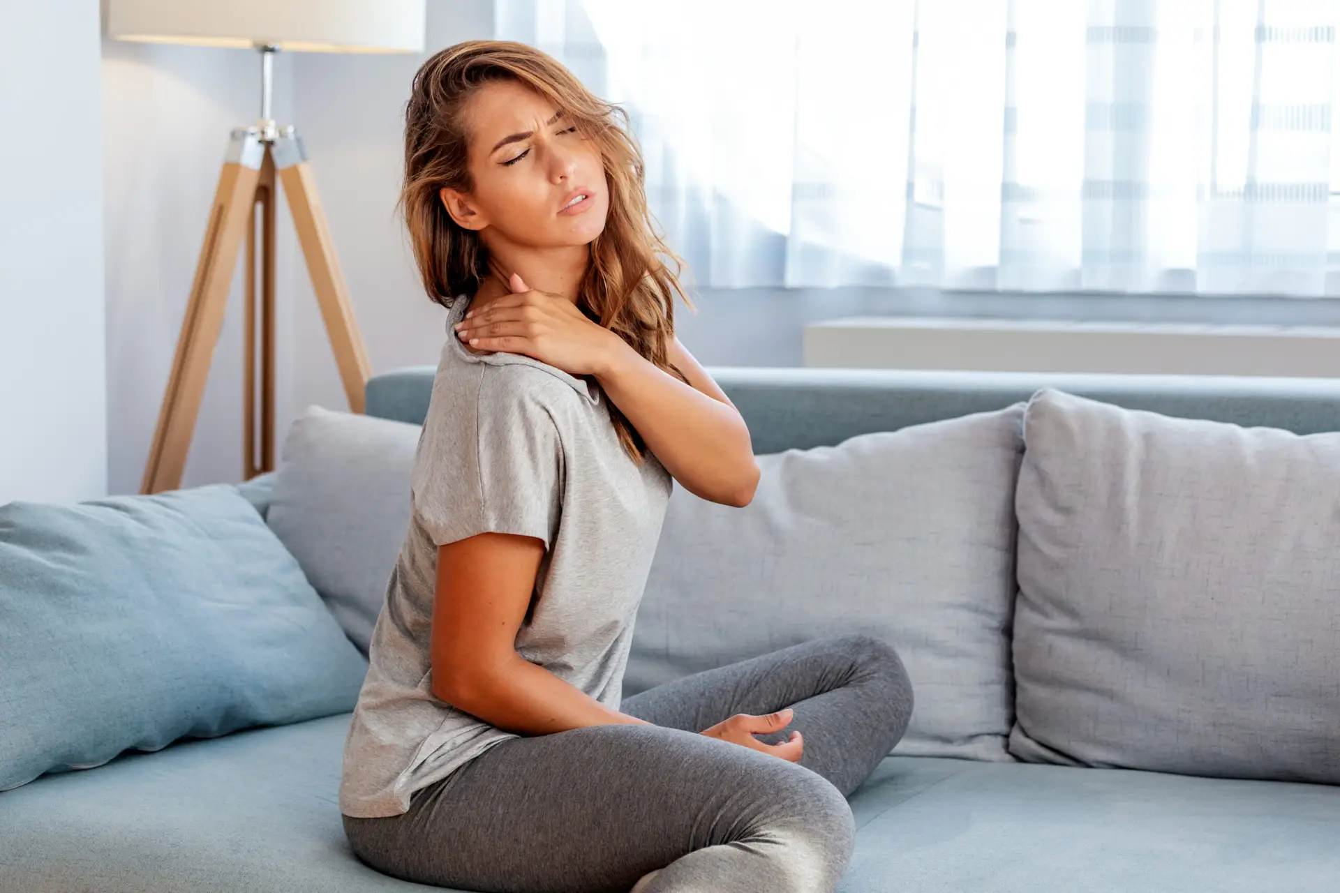 Pain in the shoulder. Upper arm pain, People with body-muscles problem, Woman sitting on the bed and holding painful shoulder with another hand image
