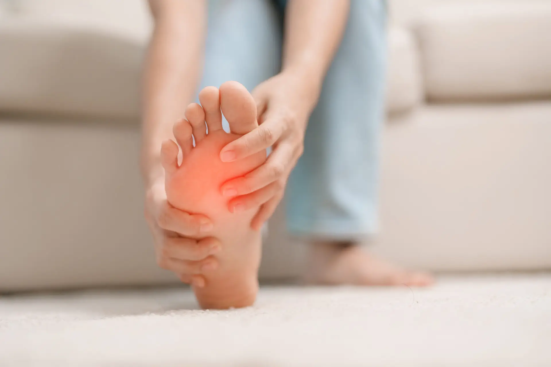 woman having barefoot pain during sitting on couch at home.