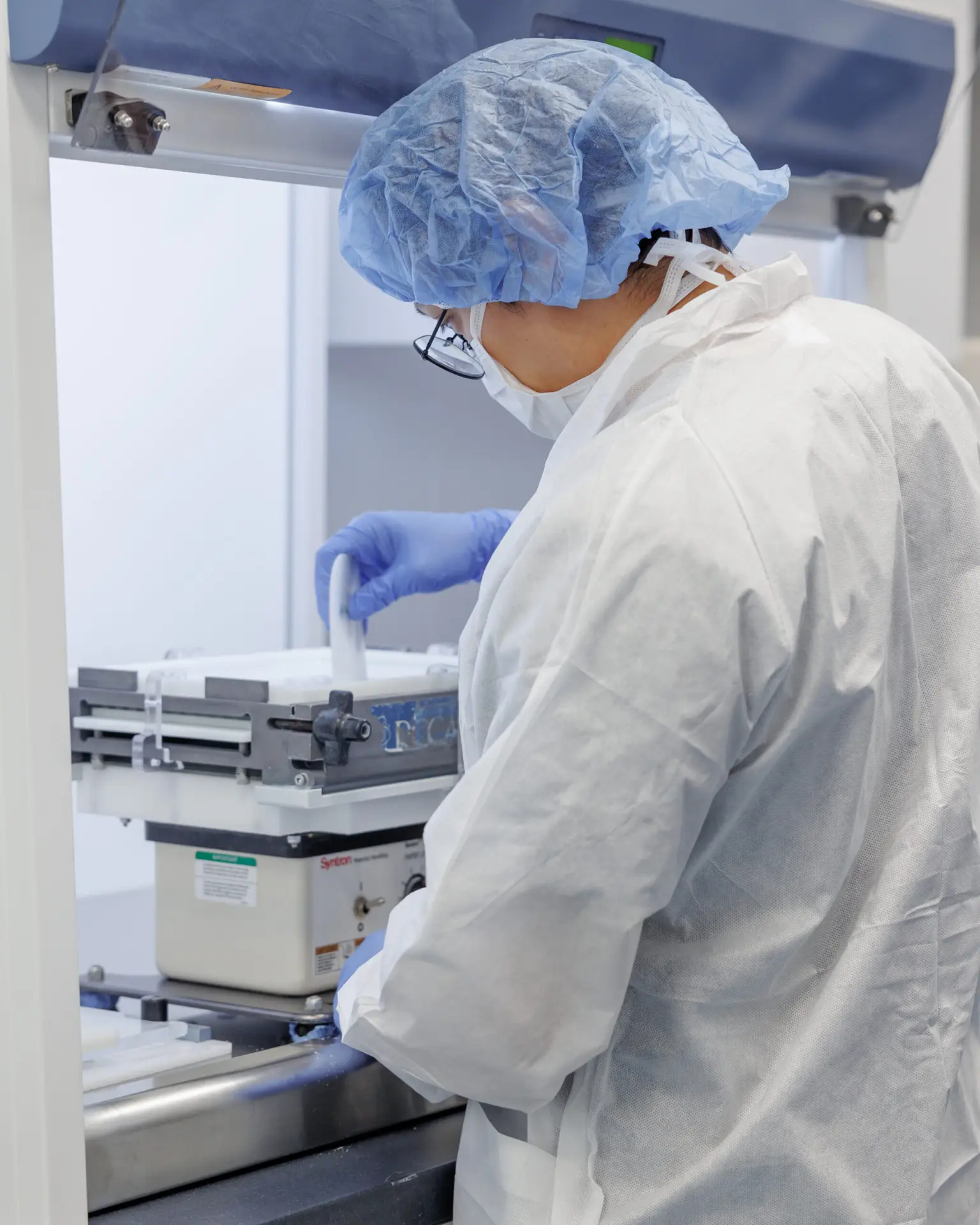 Person in lab coat preparing samples.